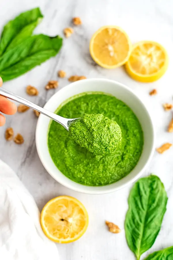 Spoonful of spinach walnut pesto being lifted from the bowl.