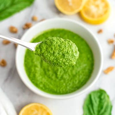 Large spoonful of spinach walnut pesto over a bowl.
