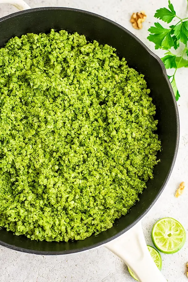 Cast iron skillet filled with green cauliflower rice.