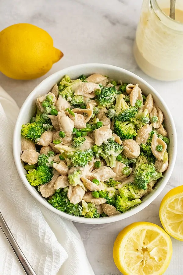 Bowl filled with tahini pasta paired with broccoli and peas. 