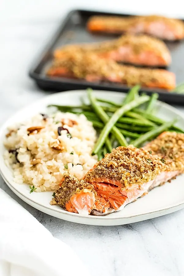 White plate with pecan crusted salmon, green beans and cauliflower rice.