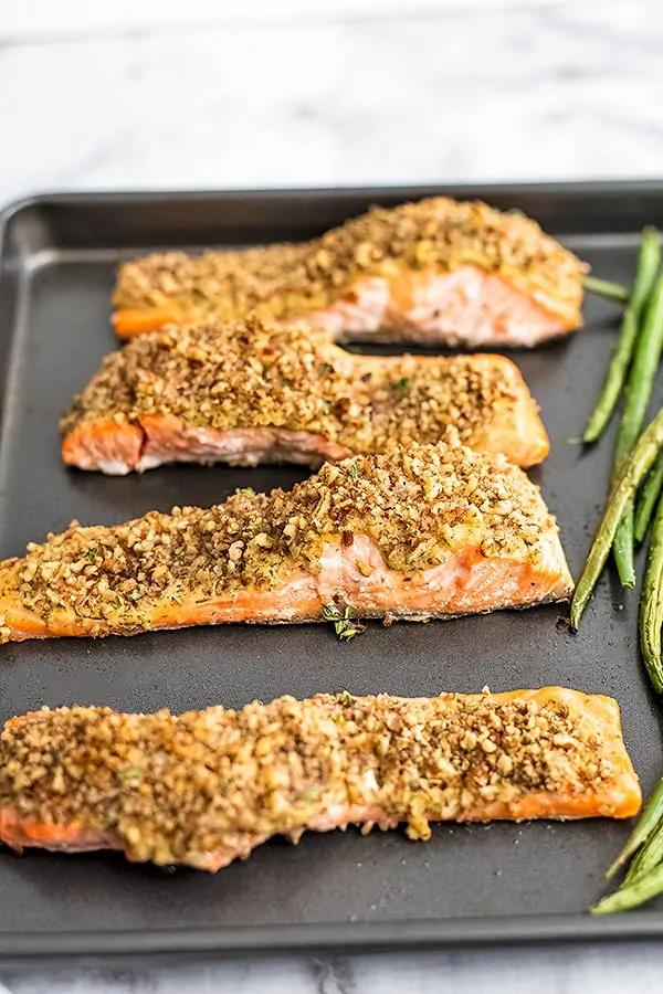 4 filets of pecan crusted salmon on a baking sheet.