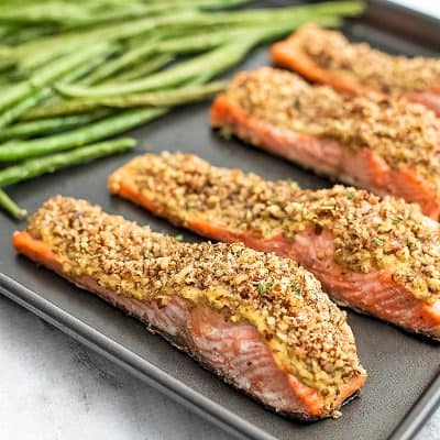 Baking sheet with 4 pieces of pecan salmon and green beans.