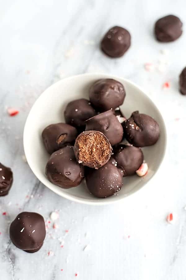 Bowl of chocolate protein energy balls with a single truffle having a bite taken.