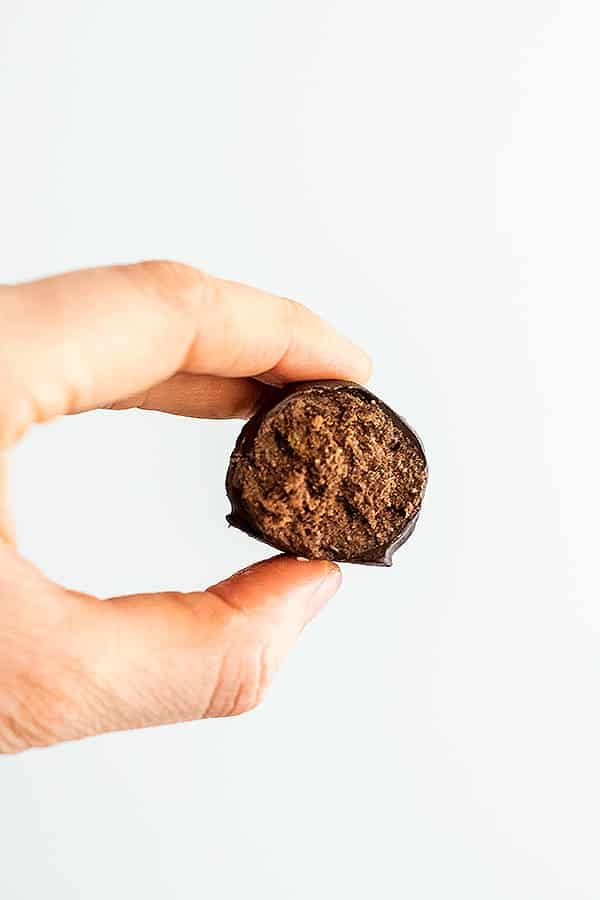 Hand holding a single peppermint truffle with bite taken.