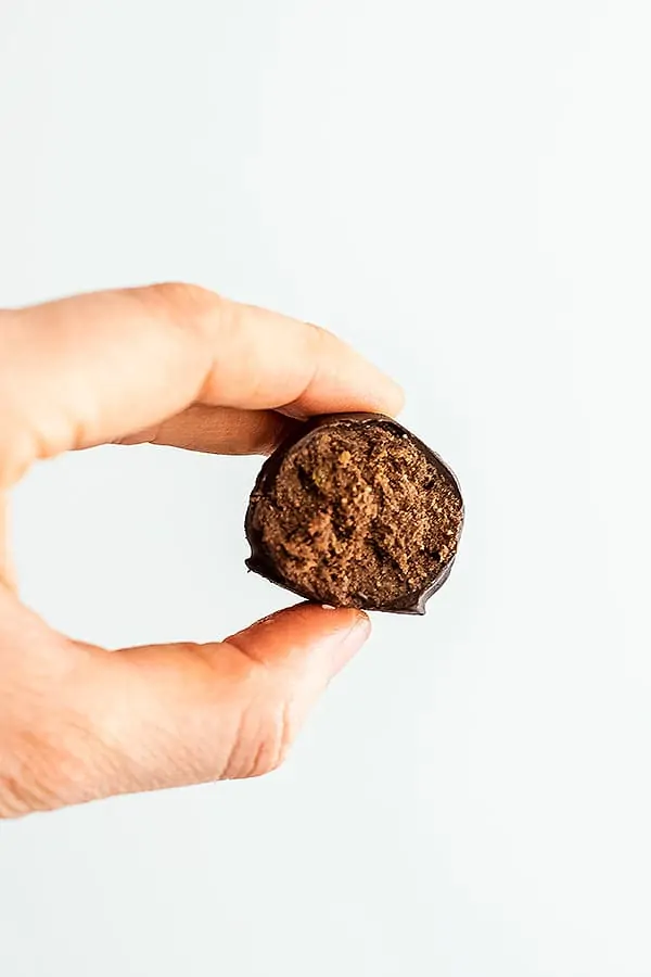 Hand holding a single peppermint truffle with bite taken.