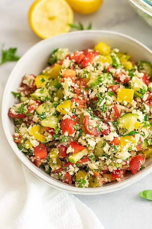 Large white bowl filled with cauliflower tabbouleh.