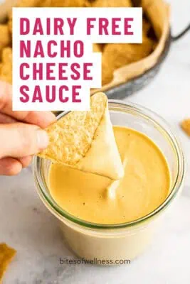 Tortilla chip being dipped in dairy free nacho cheese sauce.