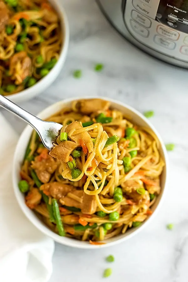 Fork in a bowl full of Asian Chicken and pasta.