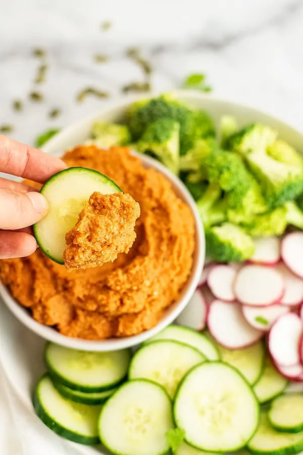 Cucumber topped with spicy carrot dip with a tray of veggies.