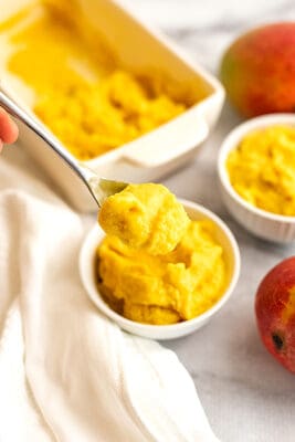 Spoonful of mango frozen yogurt over a bowl.