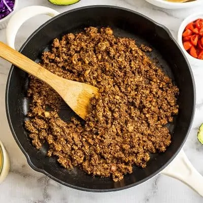 Skillet with mushroom walnut taco meat and wooden spoon.