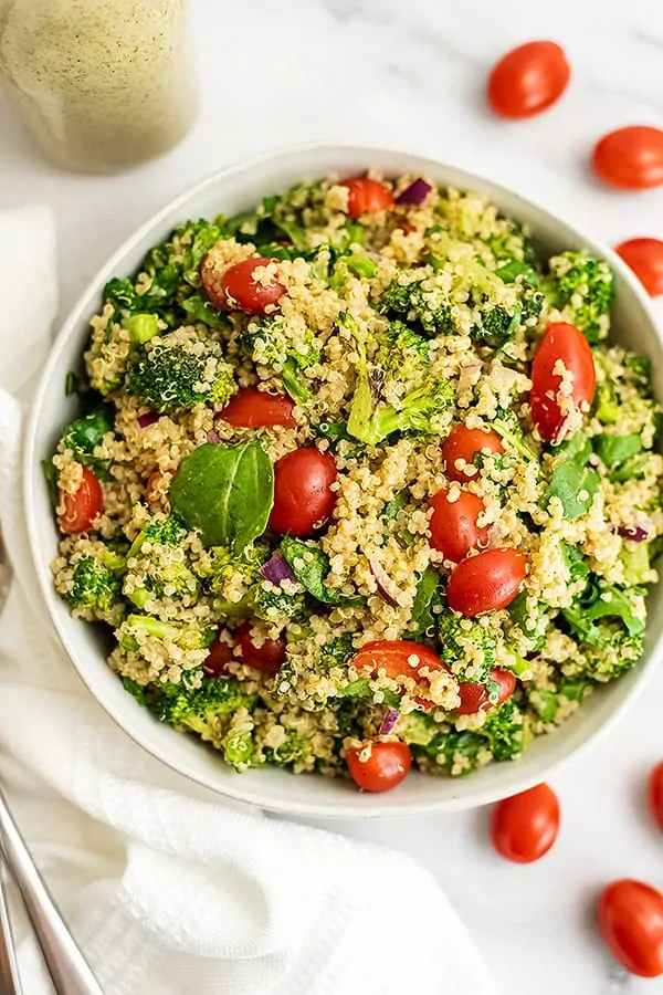 Tomatoes around a bowl filled with italian quinoa salad.