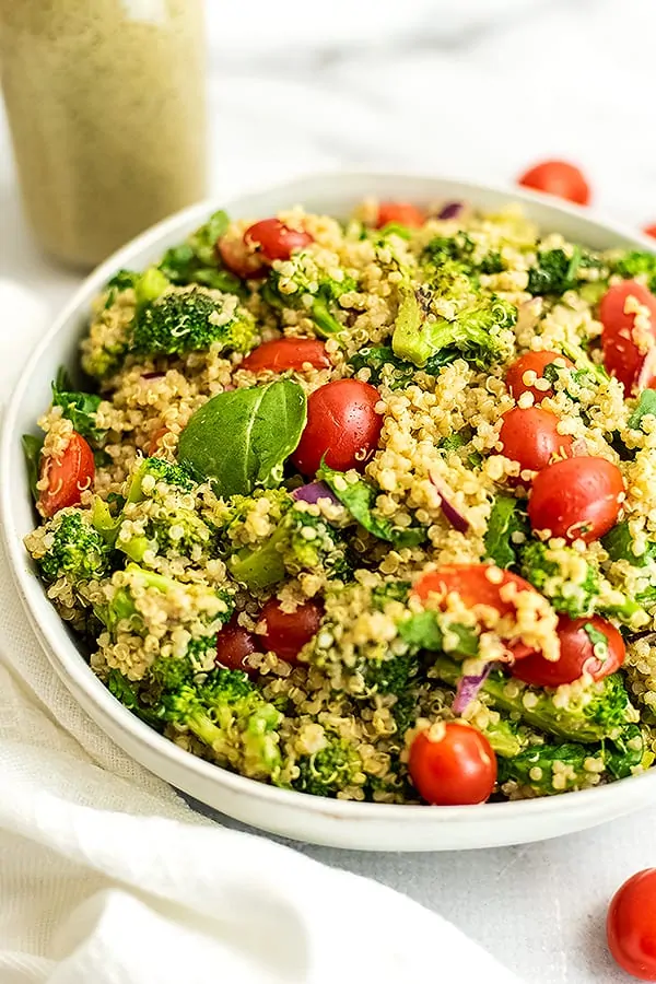 Italian quinoa salad in a bowl with Italian dressing in background.