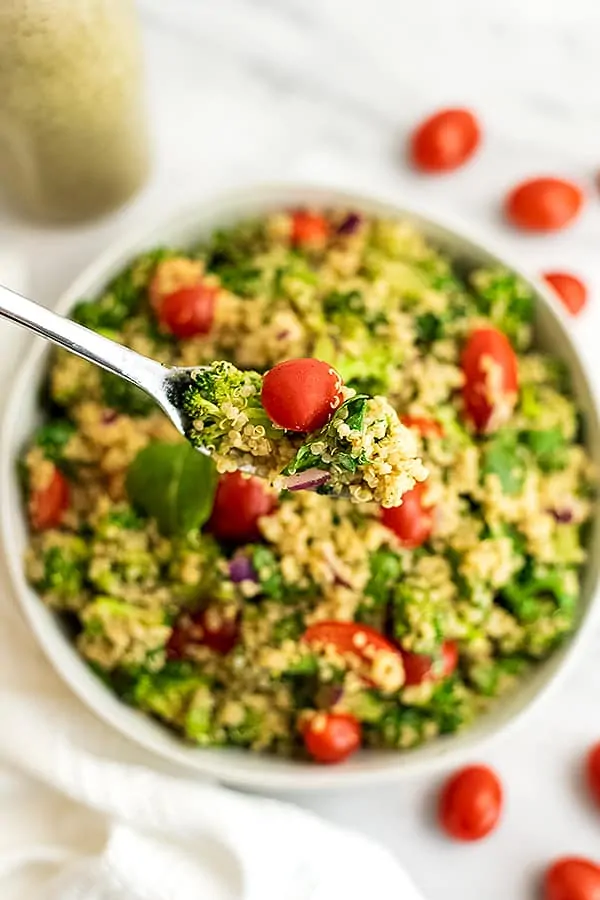 Fork scooping a bite of Italian quinoa salad from bowl.