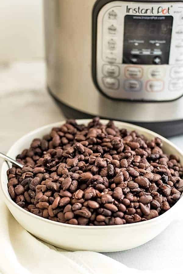 Bowl filled with black beans, instant pot in background.