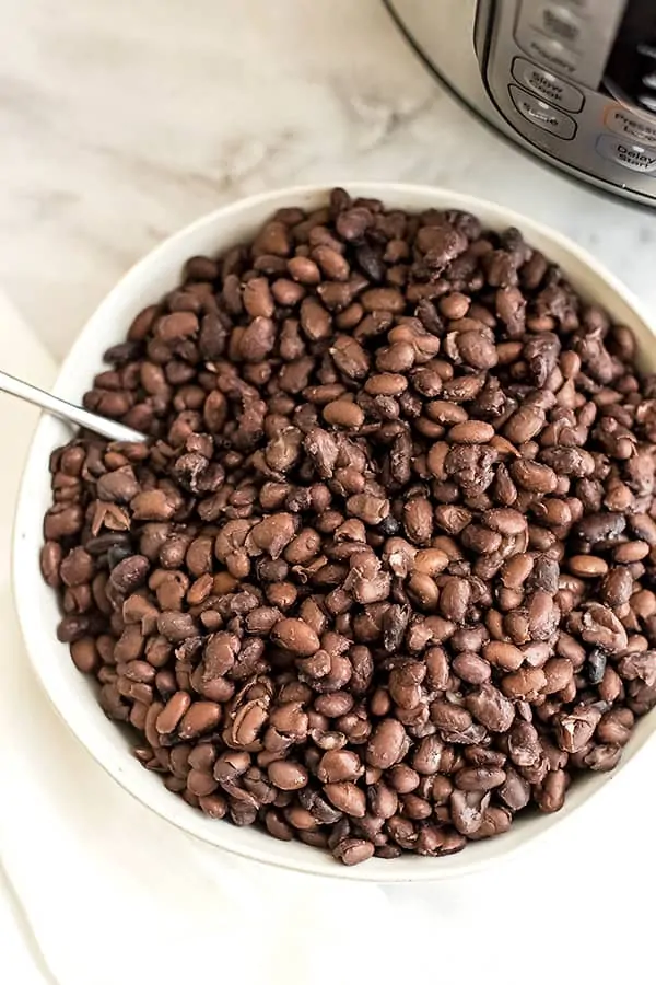 Large bowl filled with black beans with a spoon.