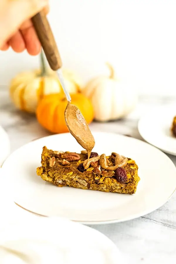 Almond butter being drizzled on pumpkin breakfast bars.