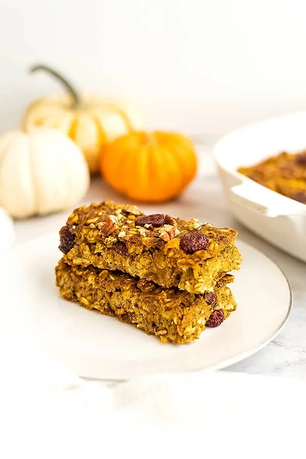 Two pumpkin oatmeal breakfast bars stacked on top of a plate.