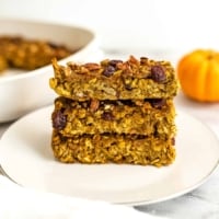 3 pumpkin breakfast bars stacked on a white plate.