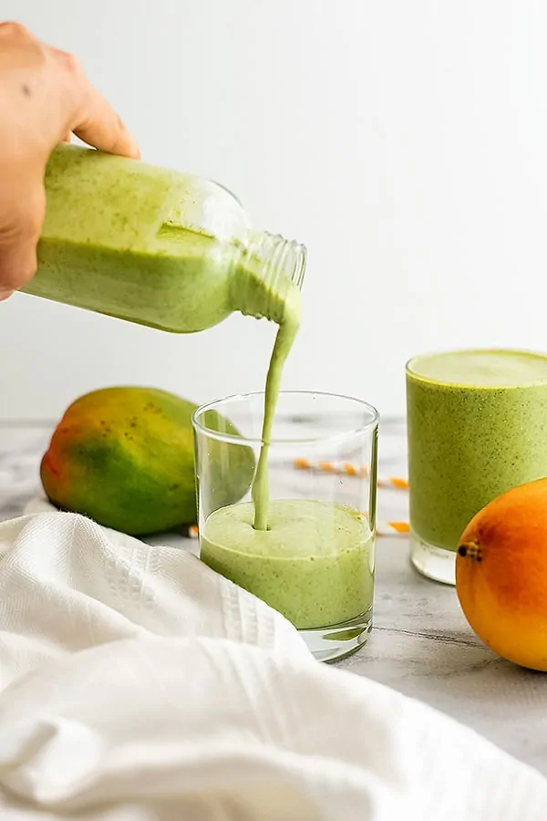 Mango kale smoothie being poured into a glass.