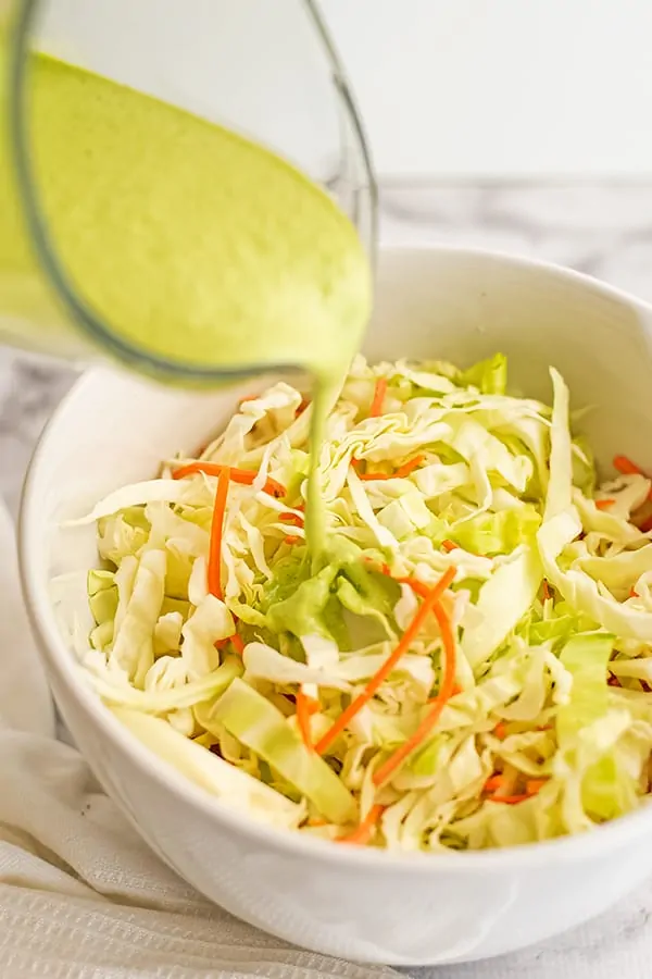 Creamy cilantro lime dressing poured over cabbage.