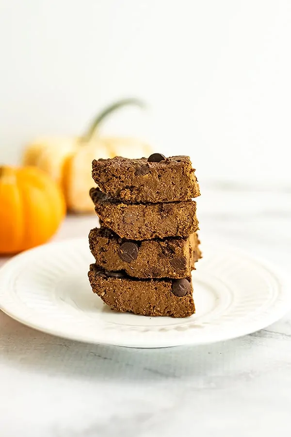 Stack of 4 pumpkin protein brownies on a plate.