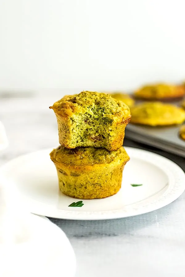 Two cheesy broccoli egg muffins stacked on a plate.