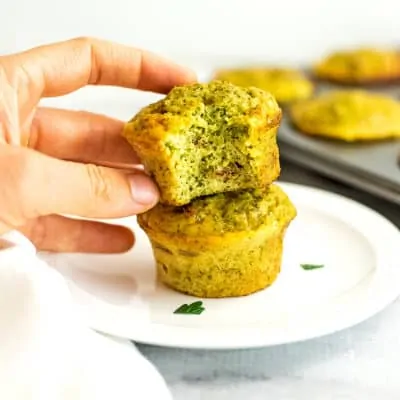 Hand holding broccoli cheese egg cups.