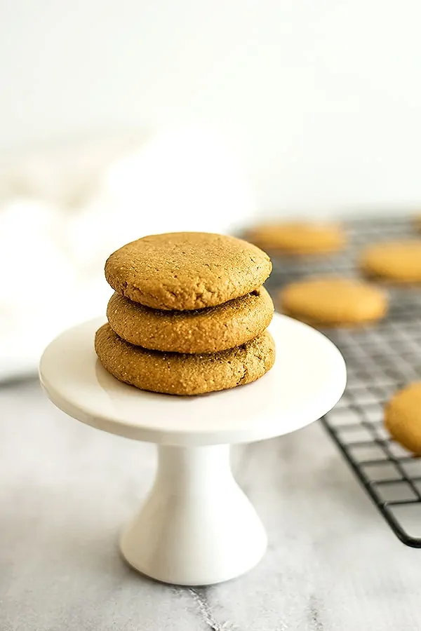 3 sunbutter cookies stacked on a white pedestal. 