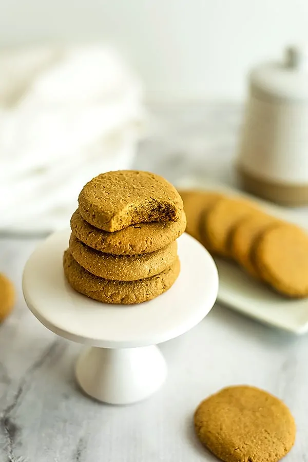 4 sunflower butter cookies on a pedestal, one has a bite taken.