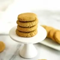 4 sunbutter cookies stacked on a white pedestal.