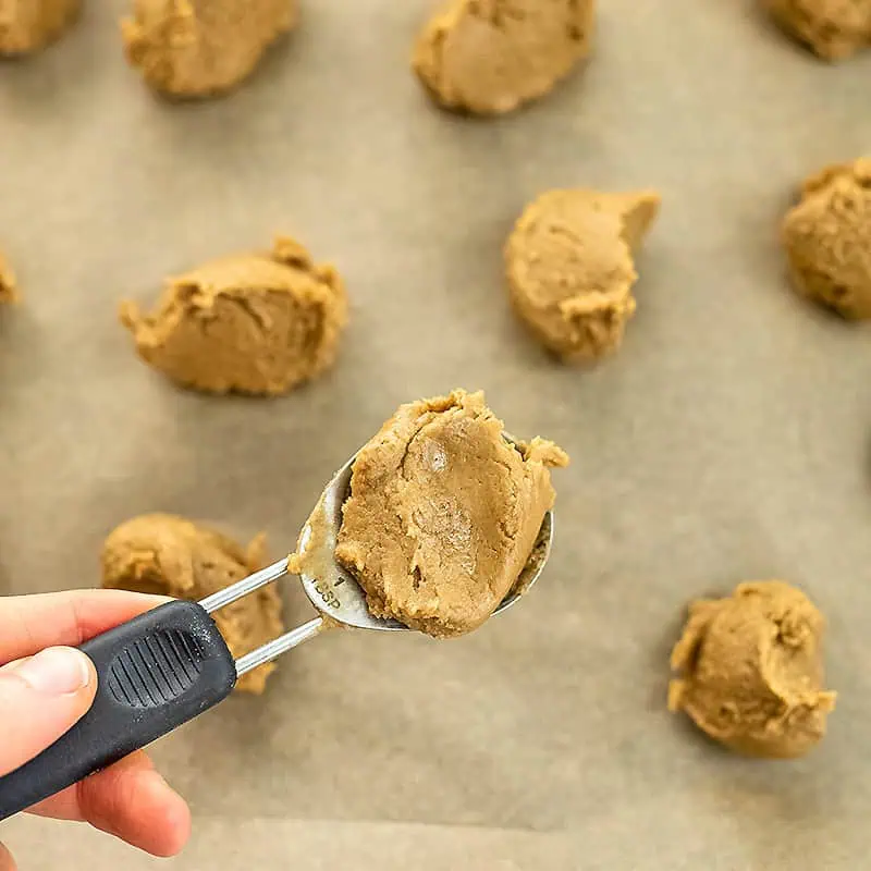 Tablespoon of protein peanut butter cookie dough being added to baking sheet.