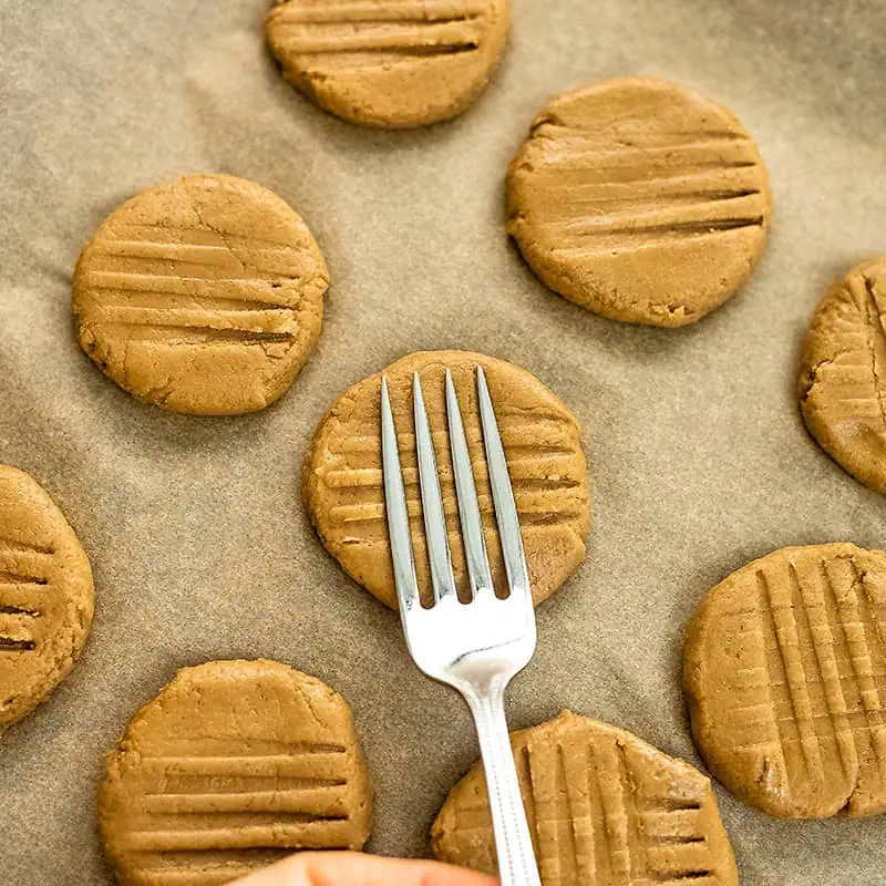 Fork adding the cross pattern to peanut butter cookies.