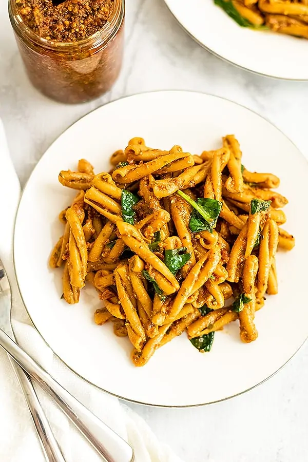 White plate filled with sun dried tomato pesto pasta.