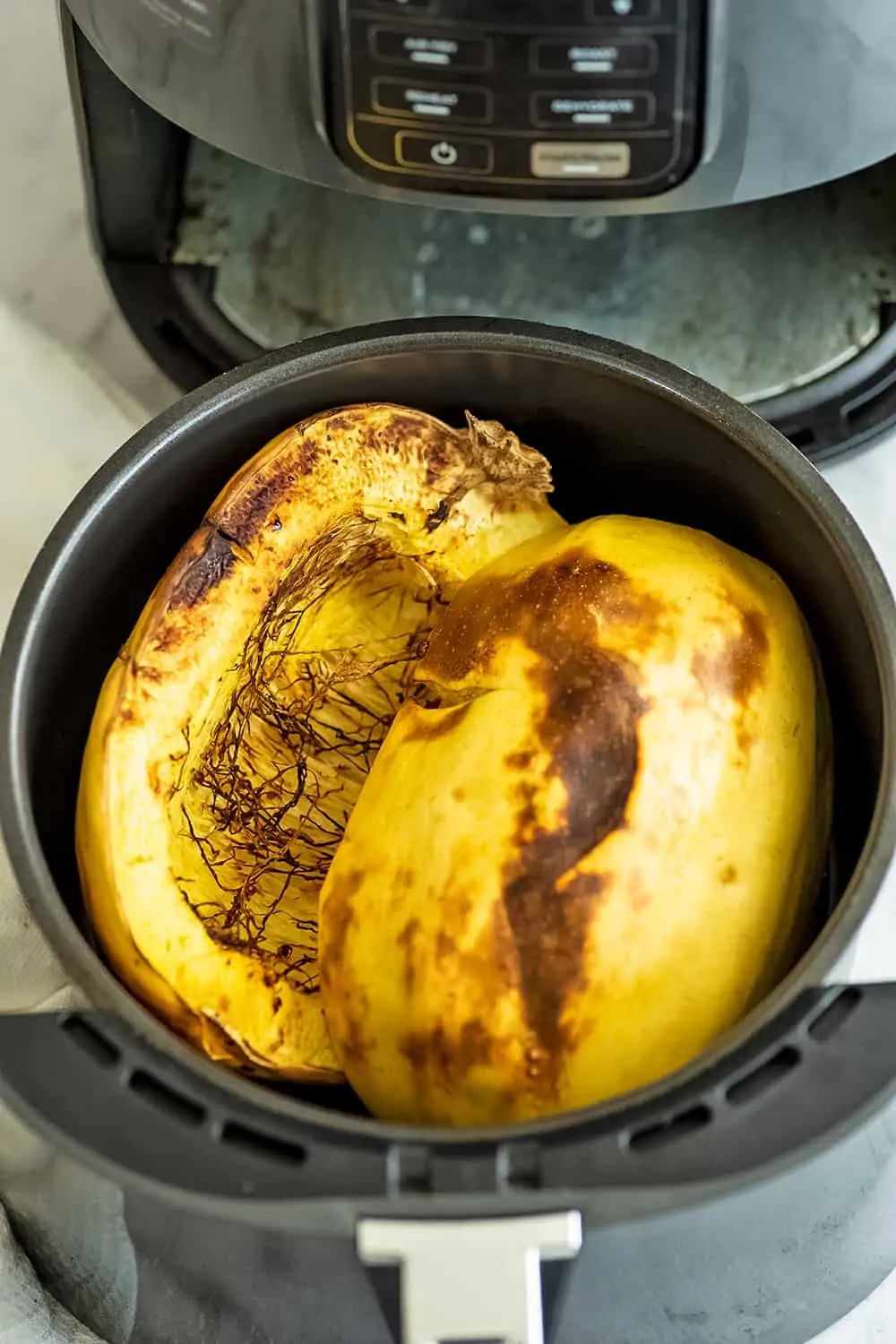 Spaghetti squash in air fryer basket after cooking.