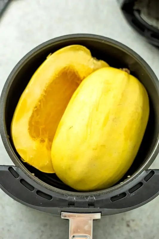 Spaghetti squash in air fryer basket before cooking.