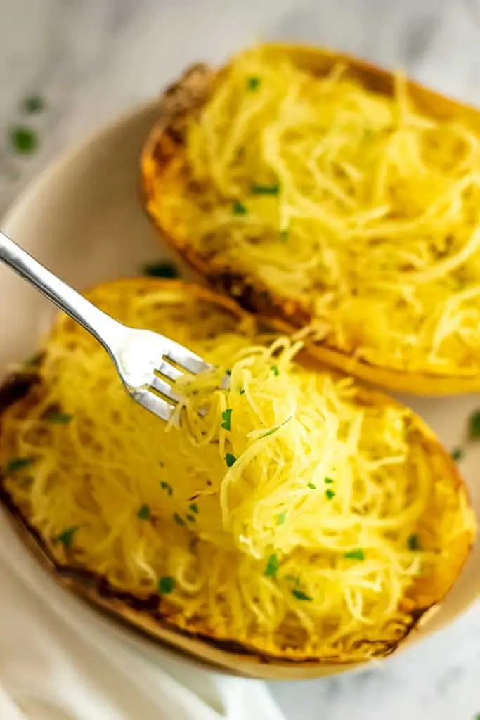 Fork holding strands of spaghetti squash after air frying.