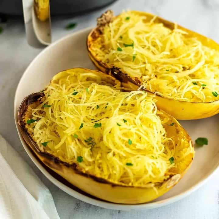 Spaghetti squash halves on a white plate after cooking.