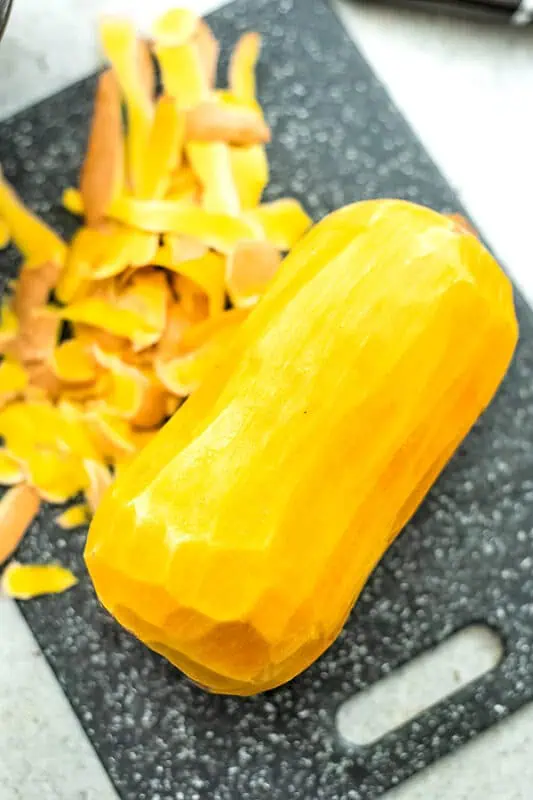 Peeled butternut squash on a cutting board.