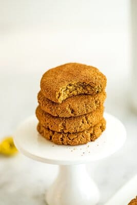 4 molasses cookies stacked on each other, the top with a bite taken out.