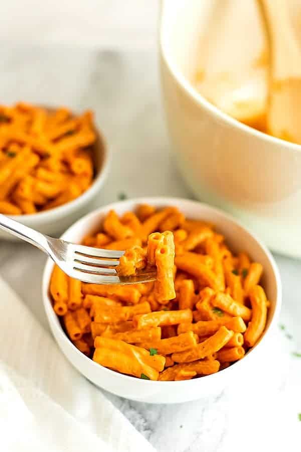 Fork holding creamy roasted red pepper pasta.