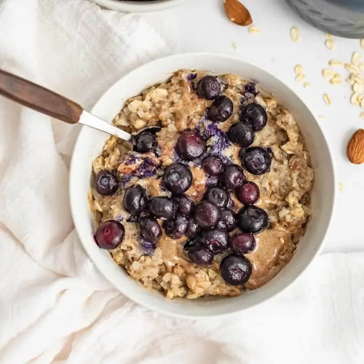 Bowl of blueberry almond oatmeal with wooden handle spoon.