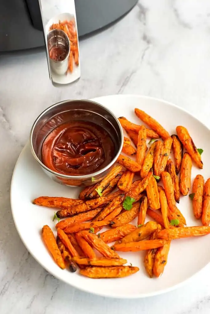 Air fryer baby carrots on a plate with ketchup.