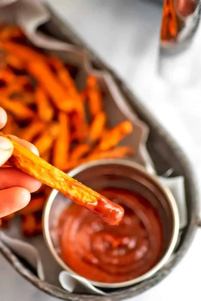 Air fryer carrot being dipped in ketchup.