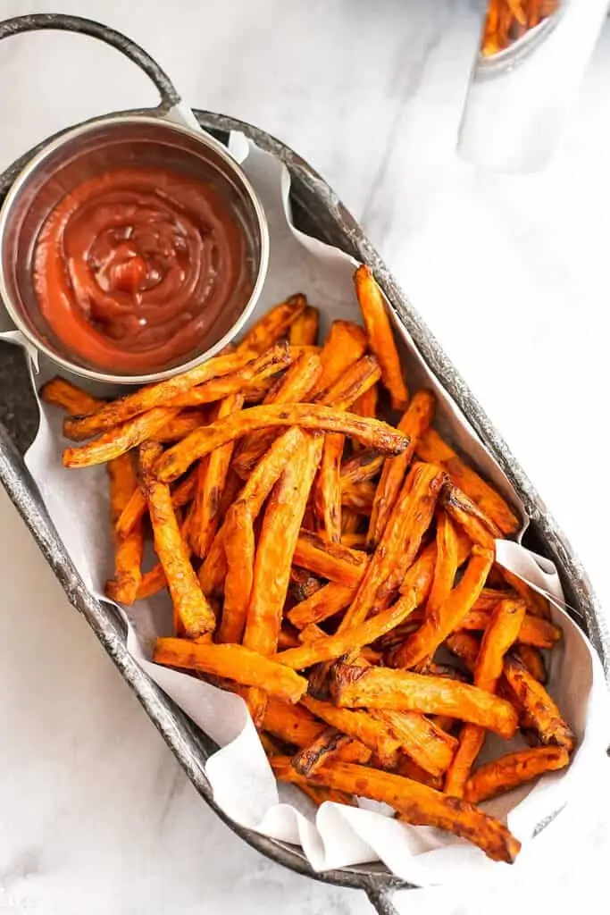 Basket full of carrot fries and ketchup.