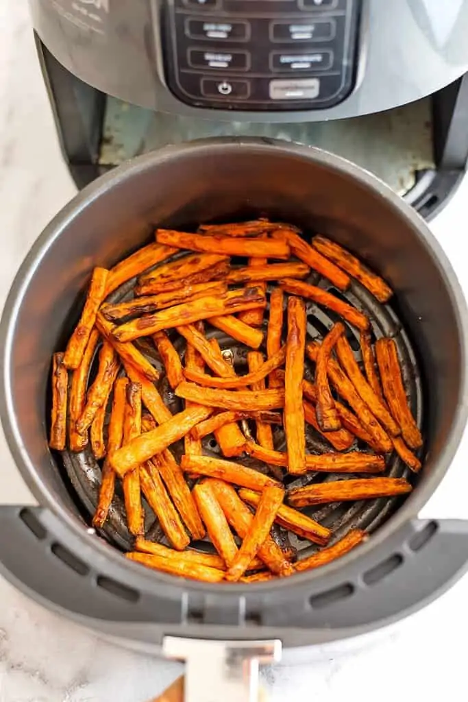 Air fryer basket full of cooked carrot fries. 