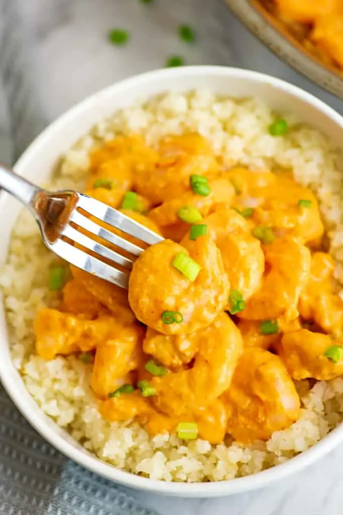 Fork grabbing a shrimp from the bowl.