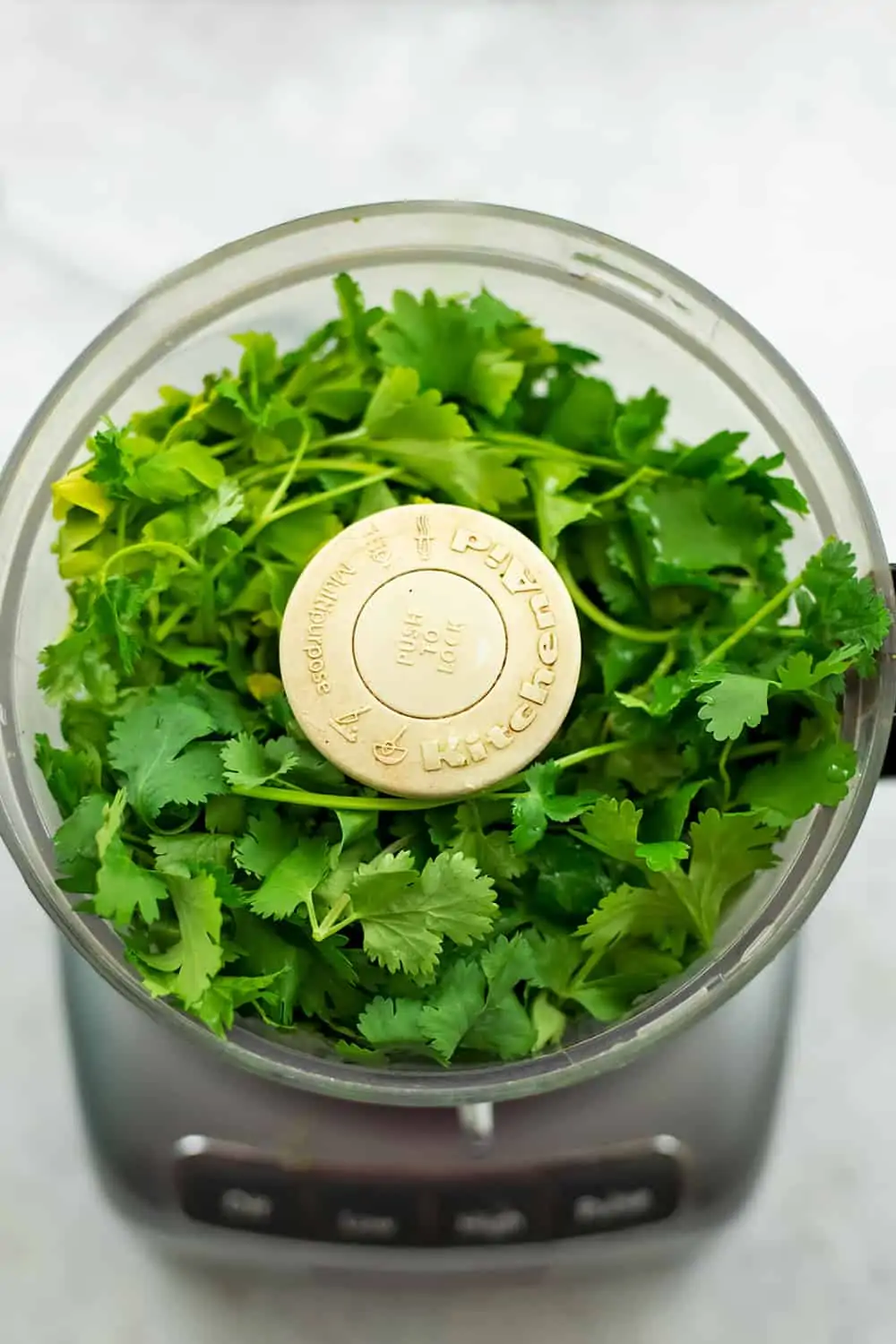 Food processor filled with cilantro and parsley.
