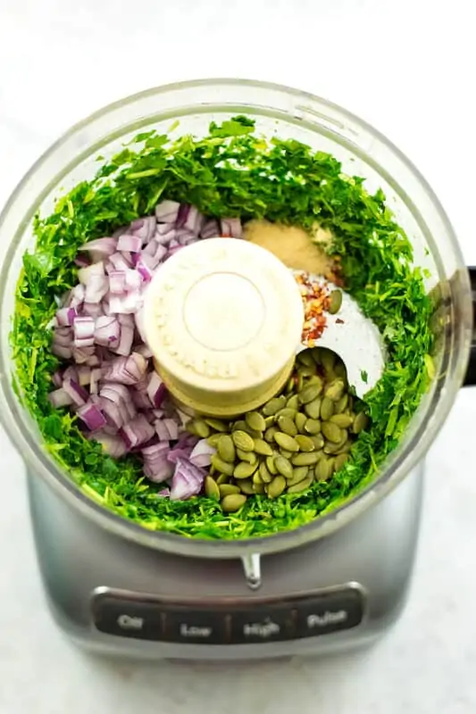 Step 2 to making chimichurri, add the onion, spices and pumpkin seeds.